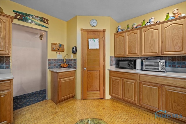 kitchen with a toaster, light countertops, and decorative backsplash