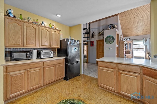 kitchen with tasteful backsplash, a toaster, light countertops, and freestanding refrigerator