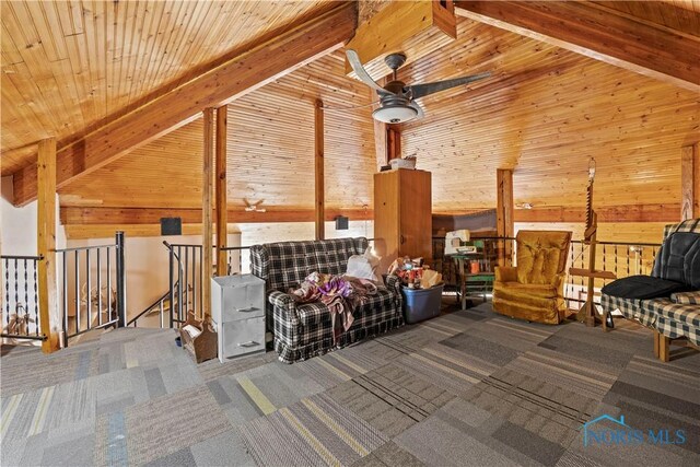 interior space featuring carpet floors, beamed ceiling, wooden walls, and an upstairs landing