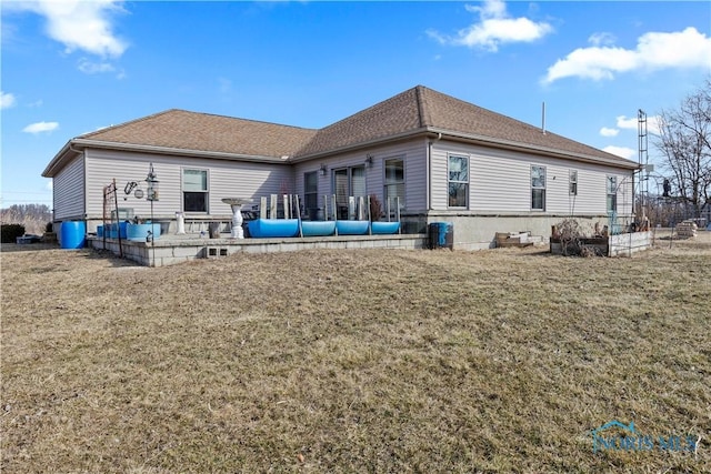 back of house with roof with shingles, a yard, and a patio