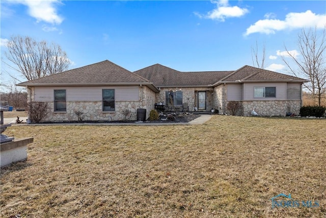 ranch-style house featuring central air condition unit, stone siding, a shingled roof, and a front lawn