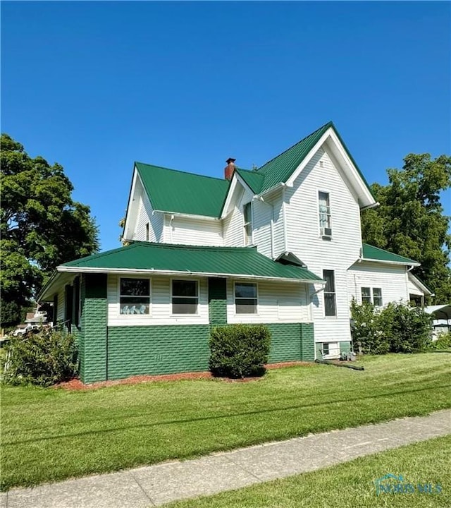 view of property exterior featuring a chimney, metal roof, and a yard