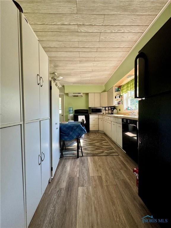 kitchen featuring wood finished floors, white cabinetry, a ceiling fan, light countertops, and black appliances