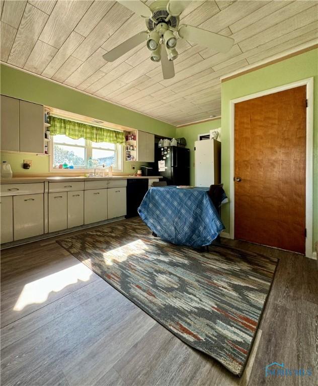 kitchen featuring wooden ceiling, light countertops, dark wood finished floors, and black appliances