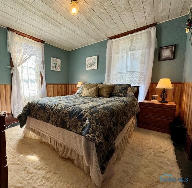 bedroom with carpet floors, a wainscoted wall, wood ceiling, and wood walls