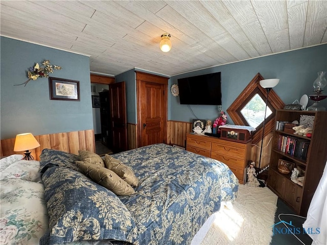 carpeted bedroom with wooden ceiling, a wainscoted wall, and wood walls