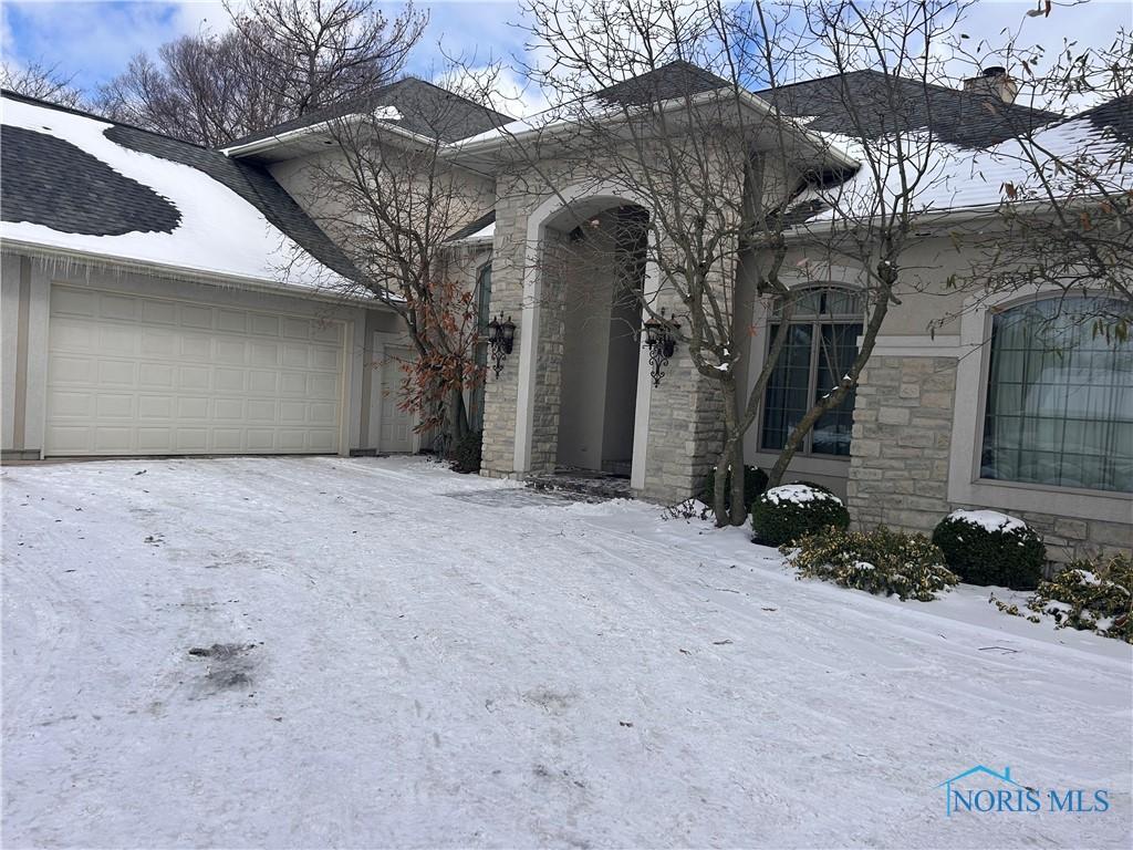 view of front of property featuring a garage, stone siding, roof with shingles, and stucco siding