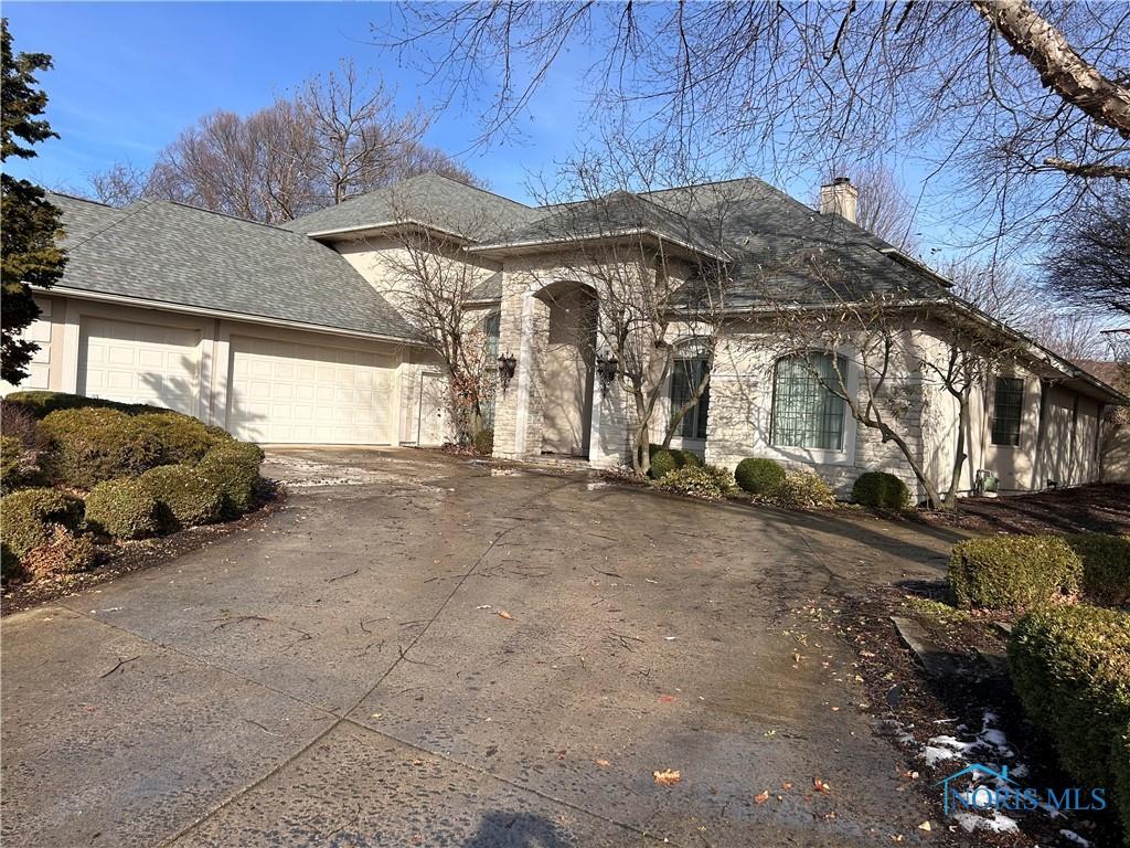 french provincial home with a garage, driveway, a chimney, and a shingled roof