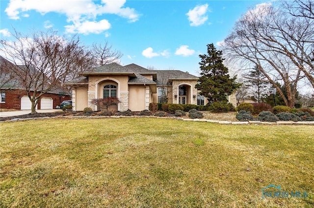 view of front of home featuring a garage, stone siding, a front yard, and stucco siding