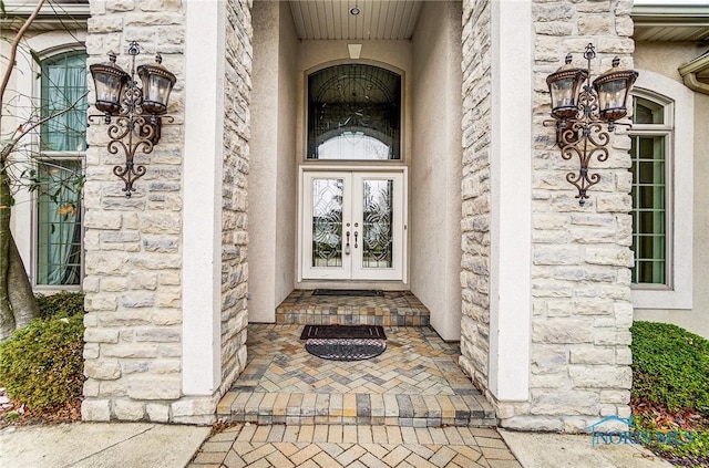 view of exterior entry featuring stone siding, french doors, and stucco siding