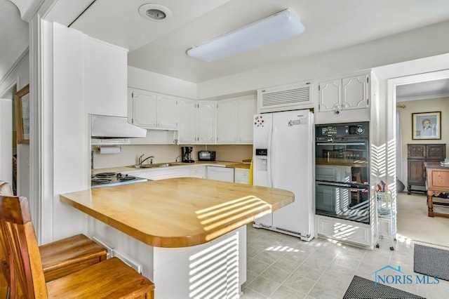 kitchen featuring white appliances, white cabinetry, light countertops, and a sink