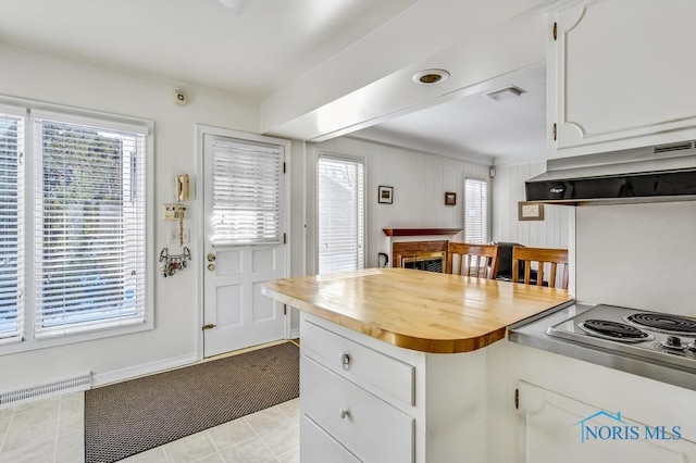 kitchen with under cabinet range hood, visible vents, a fireplace, and white cabinetry