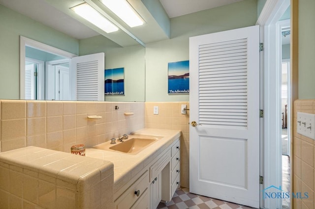 bathroom with tile patterned floors, a wainscoted wall, tile walls, and vanity