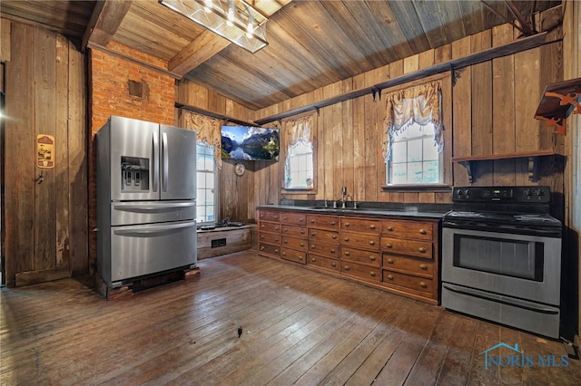 kitchen with stainless steel appliances, dark countertops, brown cabinets, and dark wood-type flooring