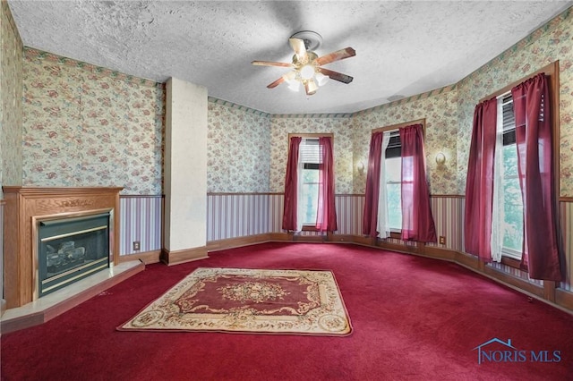 interior space with wallpapered walls, a textured ceiling, and a wainscoted wall