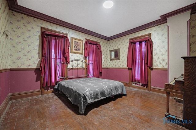 bedroom featuring wallpapered walls, wood-type flooring, and wainscoting