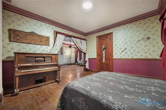 bedroom with wallpapered walls, ornamental molding, and wainscoting