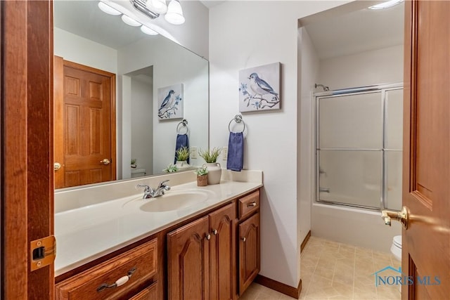 bathroom featuring toilet, bath / shower combo with glass door, vanity, baseboards, and tile patterned floors