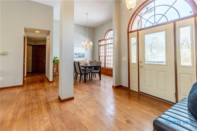 entryway with light wood-type flooring, baseboards, and a notable chandelier