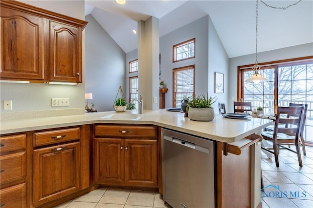 kitchen featuring a peninsula, brown cabinets, light countertops, and stainless steel dishwasher