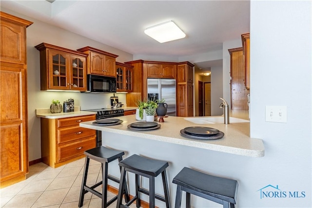 kitchen with glass insert cabinets, light countertops, and black appliances