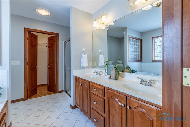 full bath featuring a stall shower, tile patterned flooring, a sink, and double vanity