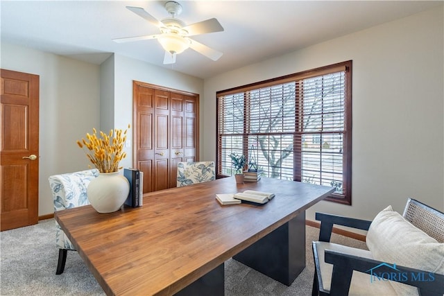 office area featuring baseboards, a ceiling fan, and light colored carpet