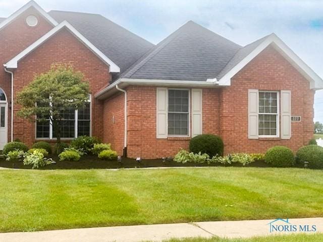 exterior space with brick siding and a front yard