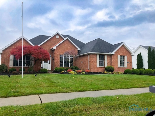 view of front facade with brick siding and a front lawn