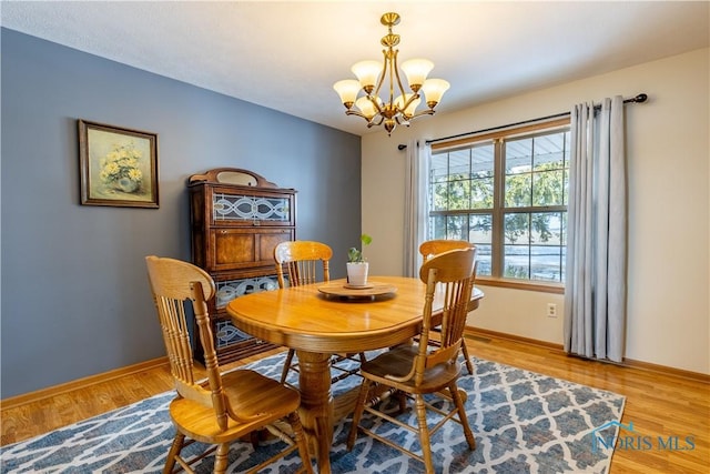 dining room featuring a notable chandelier, baseboards, and light wood-style floors