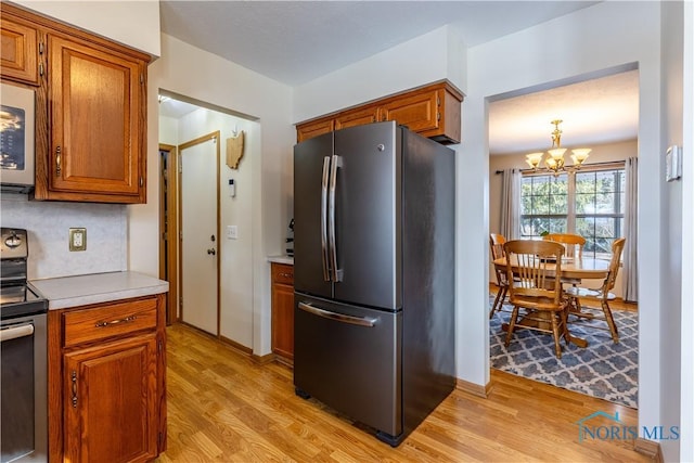 kitchen with light countertops, appliances with stainless steel finishes, brown cabinetry, and light wood-type flooring