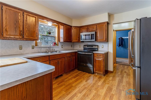 kitchen with a sink, brown cabinets, stainless steel appliances, and light countertops