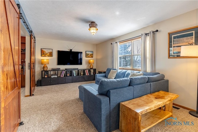 living room featuring baseboards, a barn door, a textured ceiling, and light colored carpet