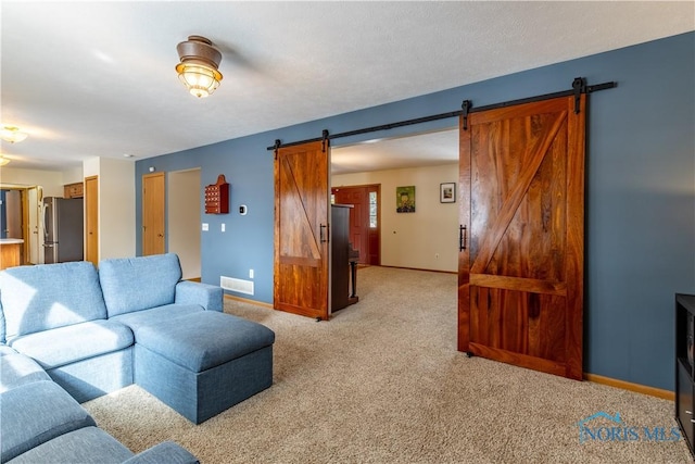 living room featuring light carpet, a barn door, visible vents, and baseboards