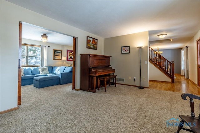 living room with baseboards, stairway, visible vents, and light colored carpet