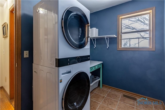 laundry room with light tile patterned floors, laundry area, visible vents, baseboards, and stacked washing maching and dryer