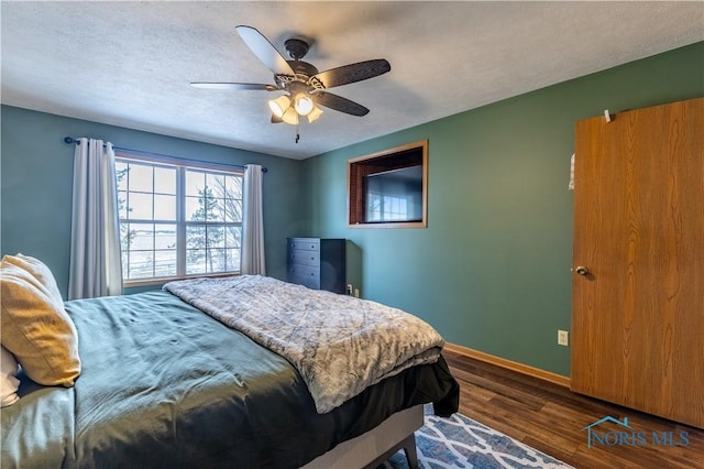 bedroom with dark wood-type flooring, ceiling fan, a textured ceiling, and baseboards