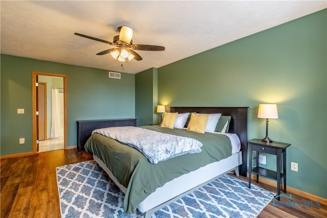 bedroom featuring baseboards, visible vents, dark wood finished floors, and a ceiling fan