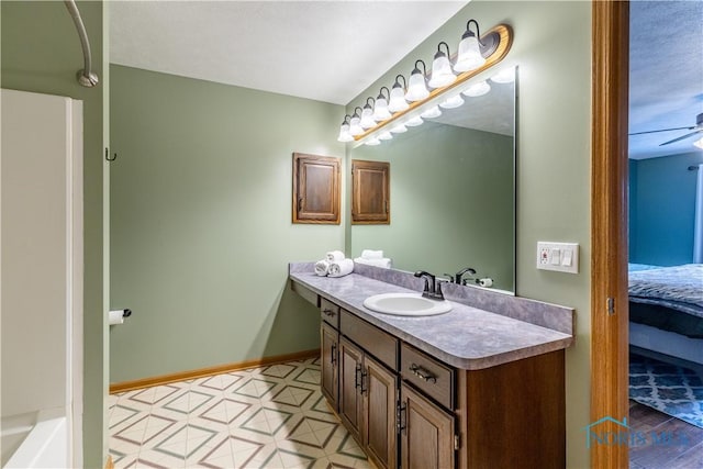 bathroom featuring ceiling fan, connected bathroom, vanity, and baseboards