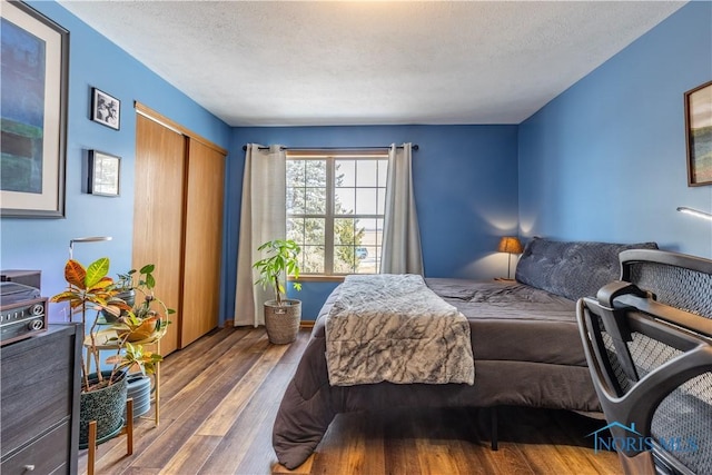 bedroom featuring a textured ceiling, a closet, and wood finished floors