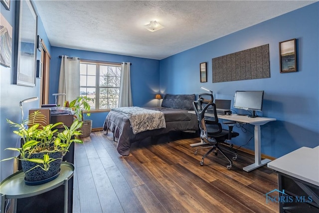 bedroom with a textured ceiling, dark wood-type flooring, and baseboards