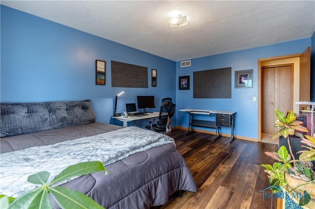 bedroom with visible vents, a textured ceiling, baseboards, and wood finished floors