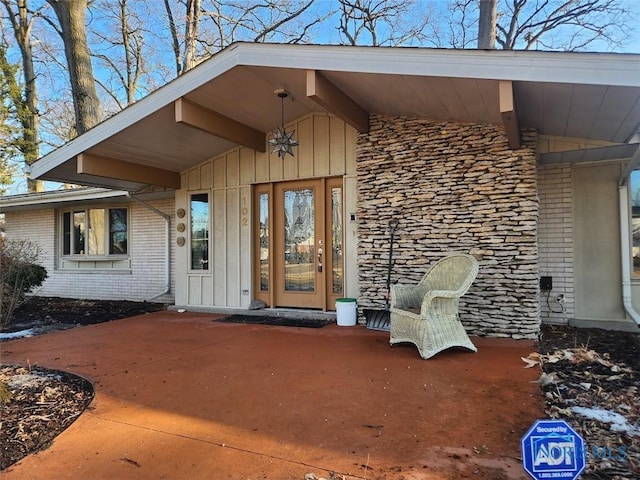 doorway to property with board and batten siding and brick siding