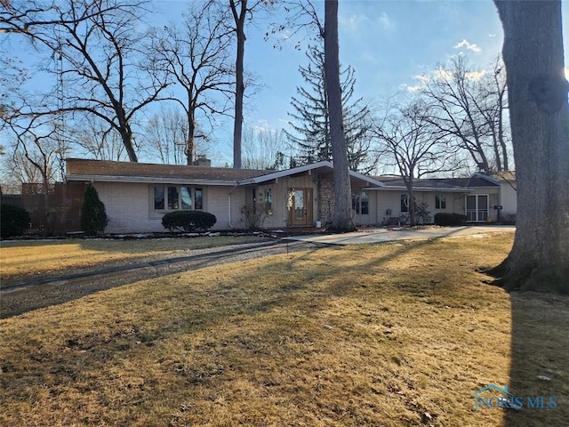 view of front of property with a chimney, a front lawn, and brick siding