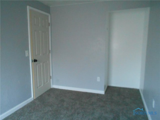 empty room featuring dark carpet and baseboards