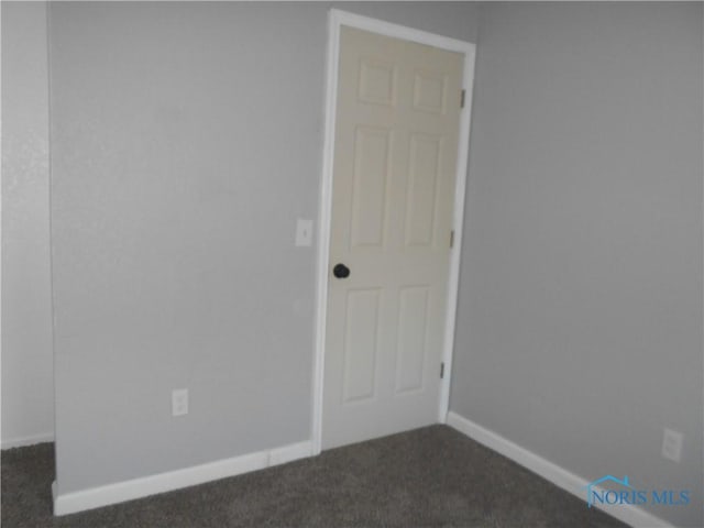 empty room featuring dark carpet and baseboards