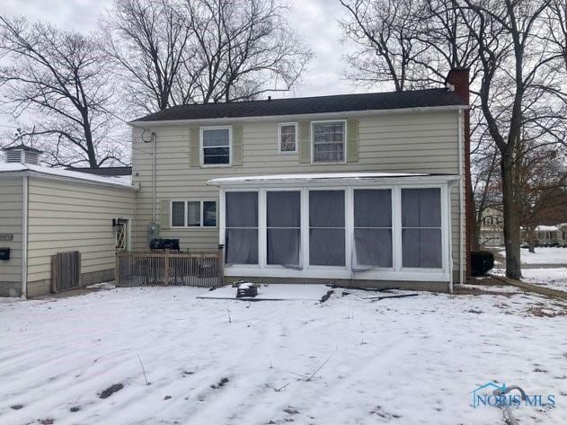 snow covered rear of property with a chimney