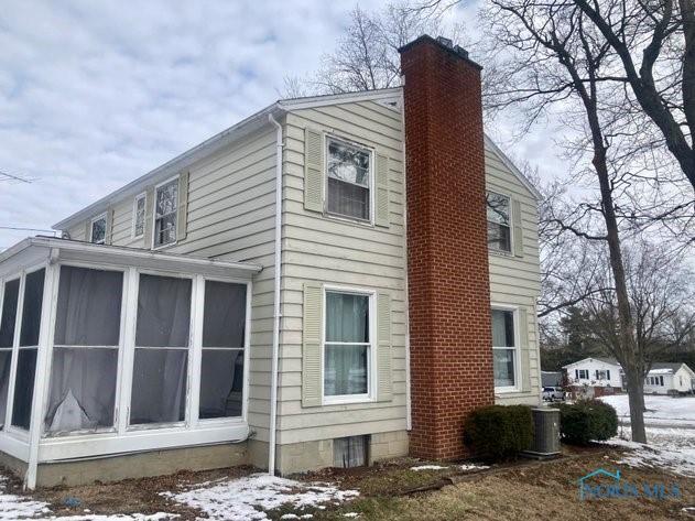 view of snow covered exterior with a chimney and a sunroom