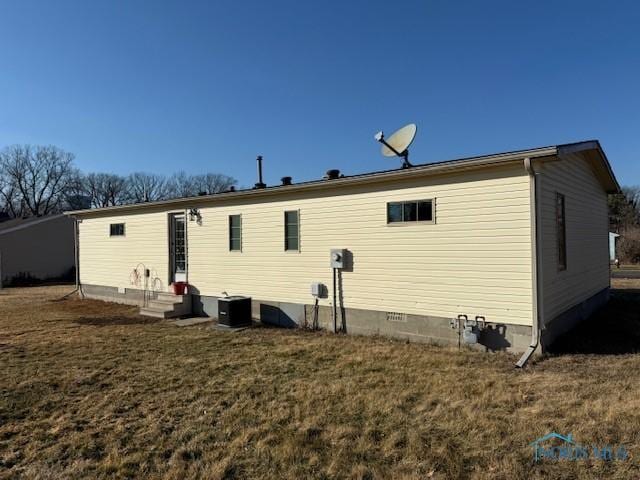 back of property featuring crawl space, a lawn, cooling unit, and entry steps