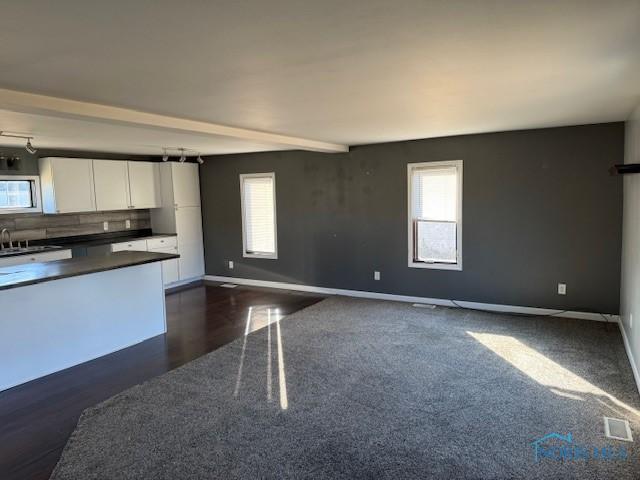 kitchen with open floor plan, dark countertops, white cabinetry, and a healthy amount of sunlight